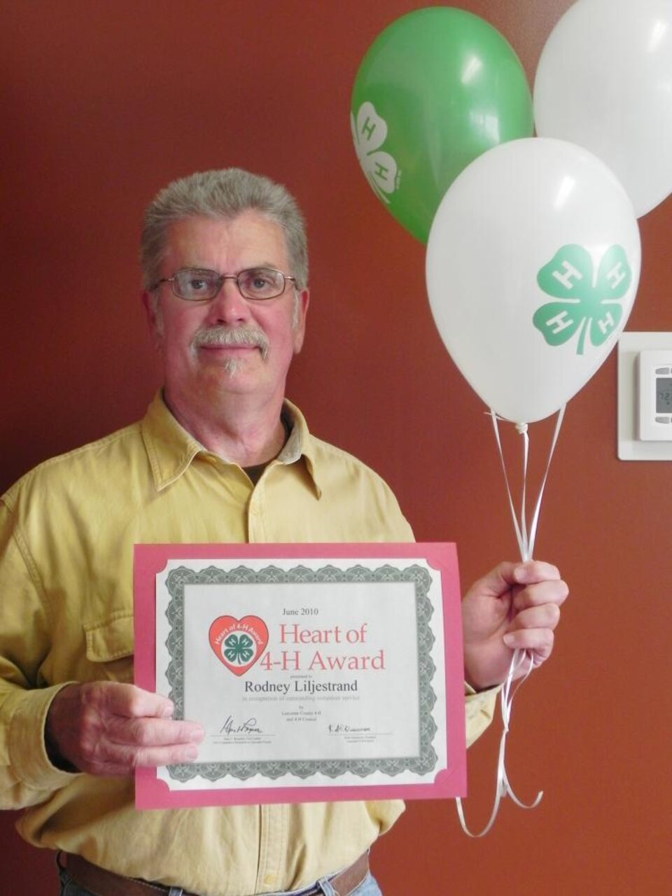 Rodney Lilestrand holding 4-H balloons and a certificate. 