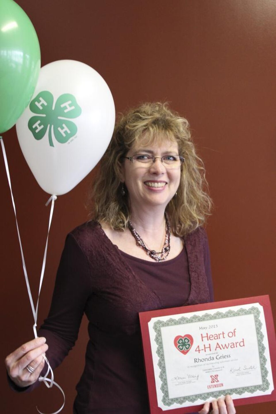 Rhonda Griess holding 4-H balloons and a certificate. 