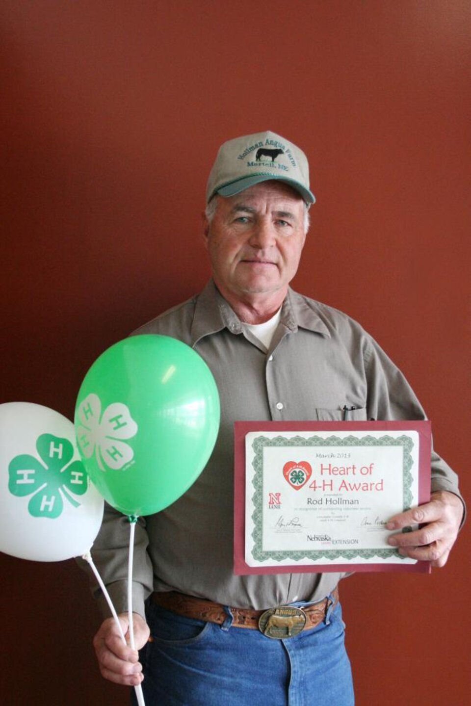 Rod Hollman holding 4-H balloons and a certificate. 