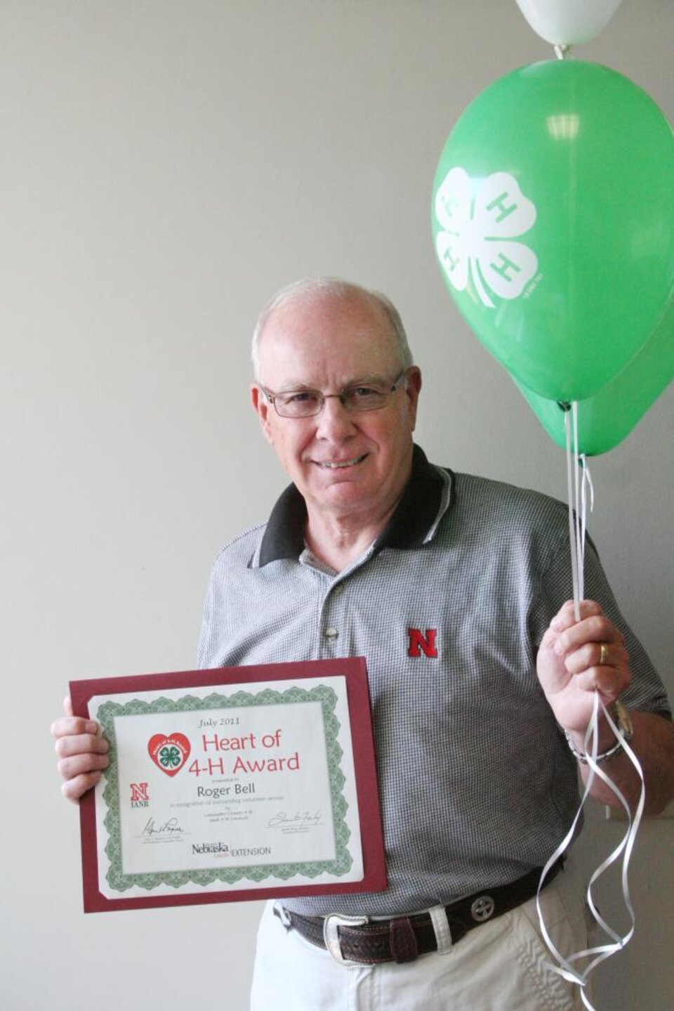 Roger Bell holding 4-H balloons and a certificate. 