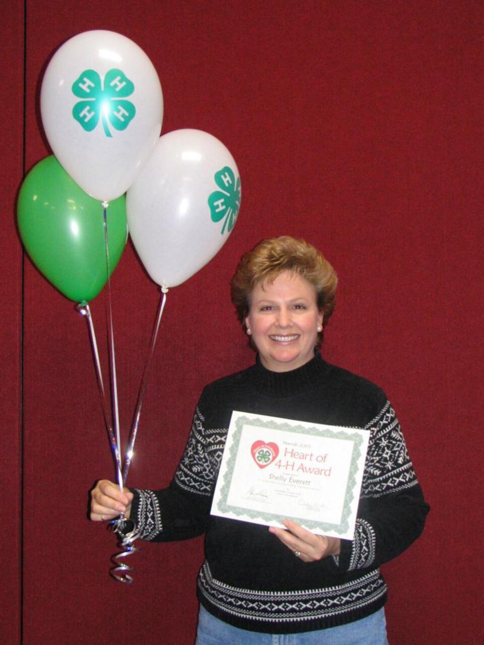 Shelly Everett holding balloons and a certificate 