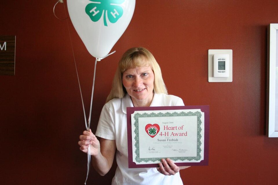 Susan Frobish holding balloons and a certificate 