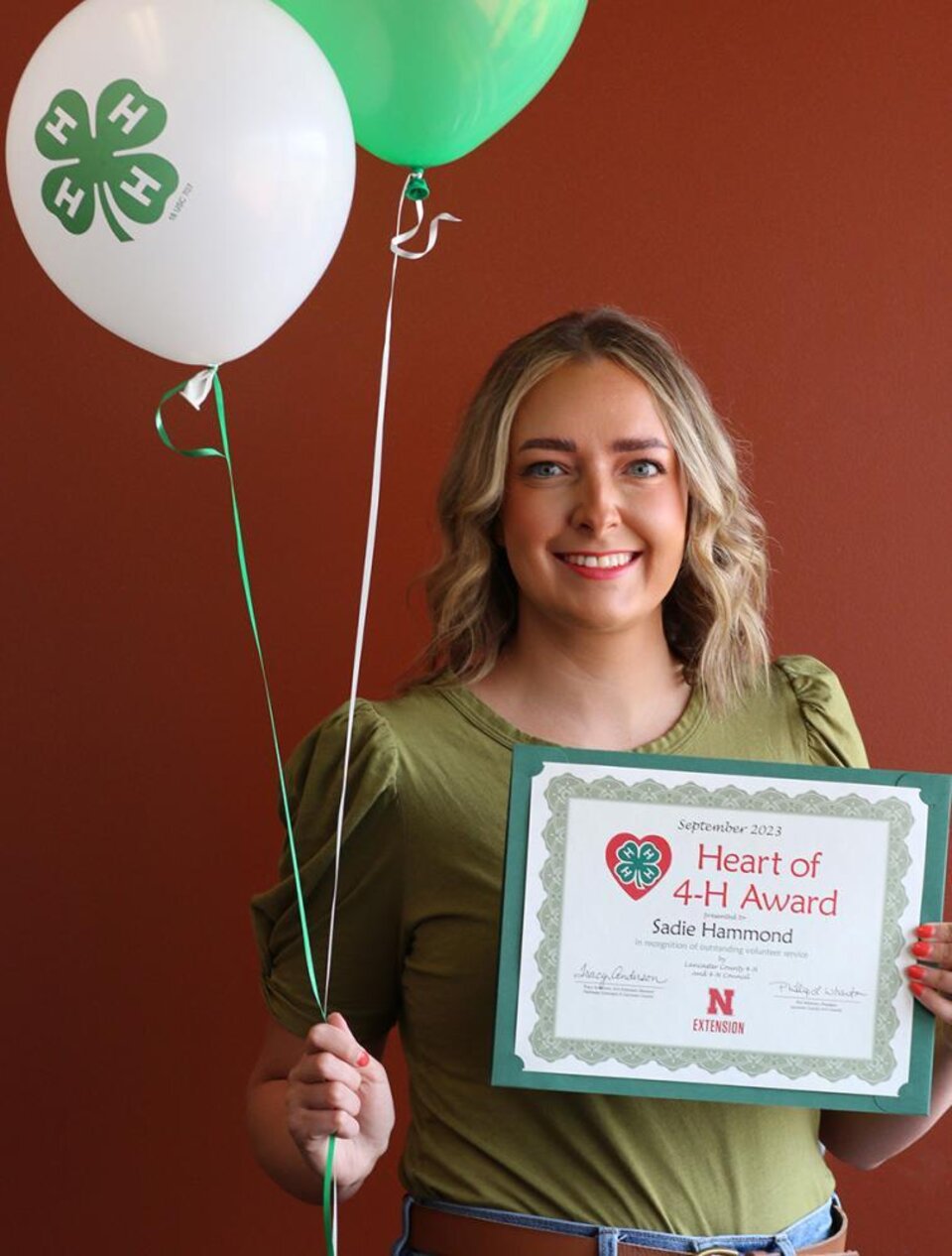 Sadie Hammond holding a 4-H certificate and balloons 