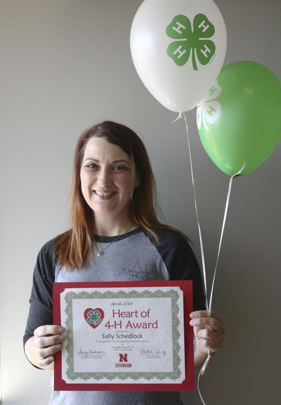 Sally Schedlock holding 4-H balloons and a certificate. 