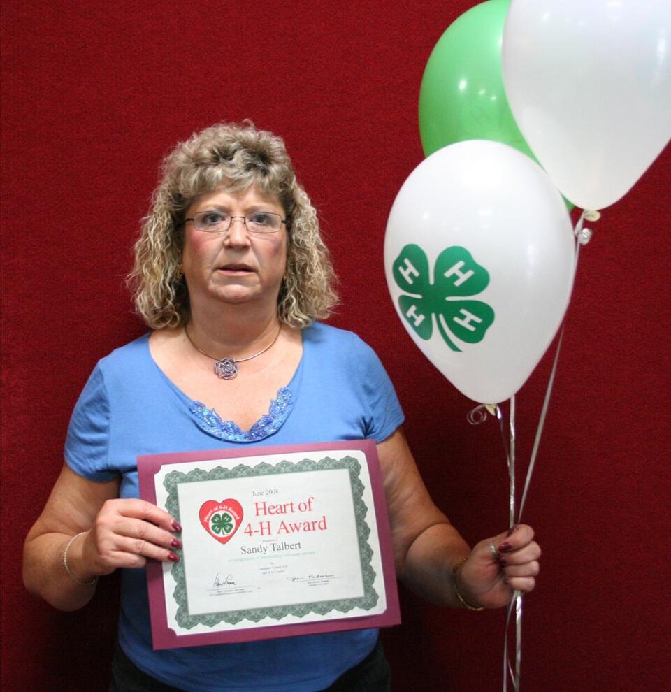 Sandy Talbert holding balloons and a certificate 