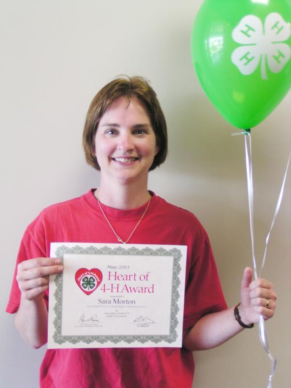 Sara Morton holding balloons and a certificate 