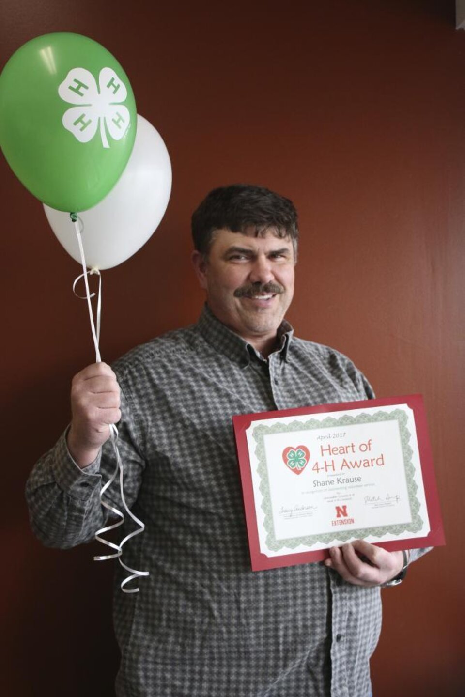 Shane Krause holding 4-H balloons and a certificate. 