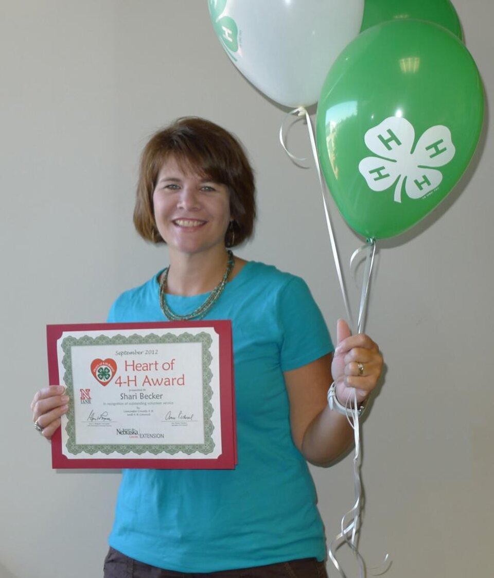 Shari Becker holding 4-H balloons and a certificate. 