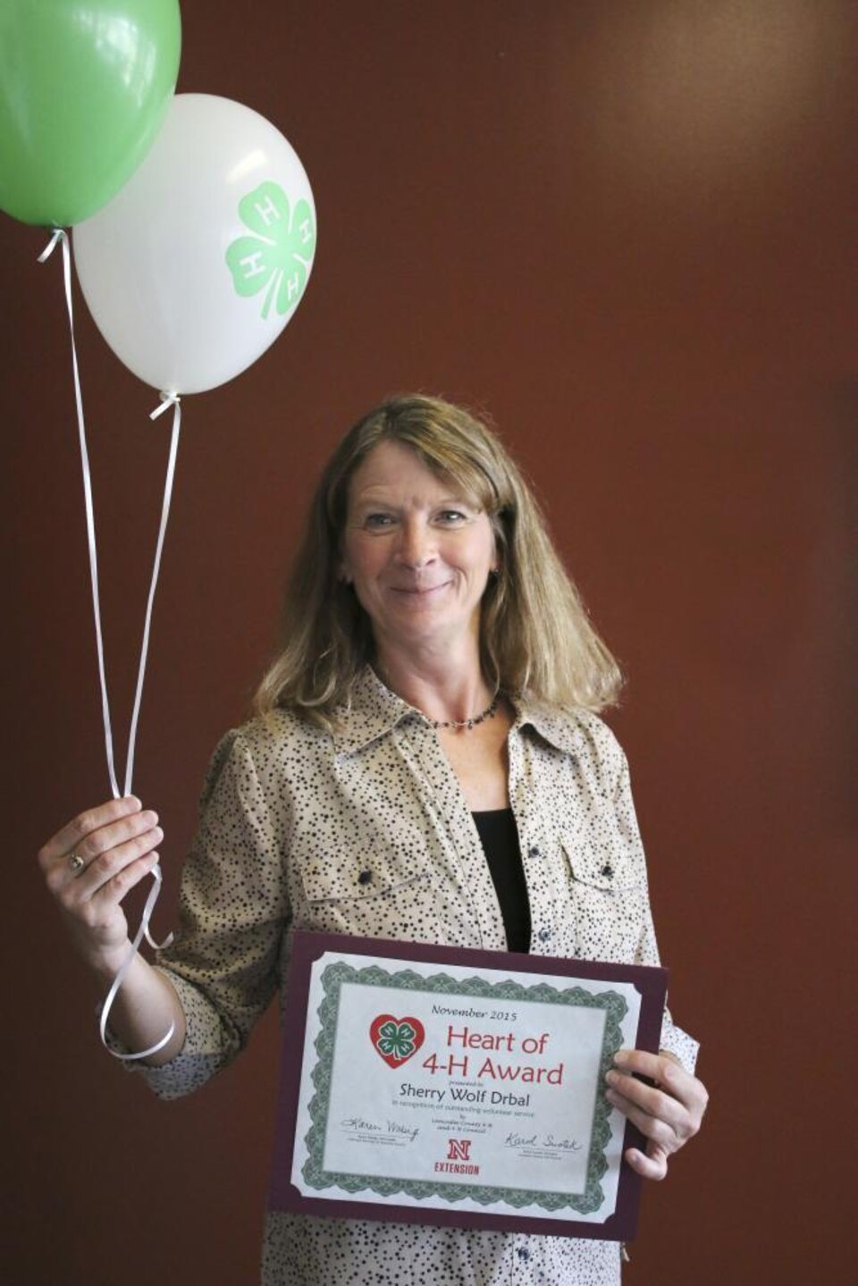 Sherry Wolf Drbal holding 4-H balloons and a certificate. 