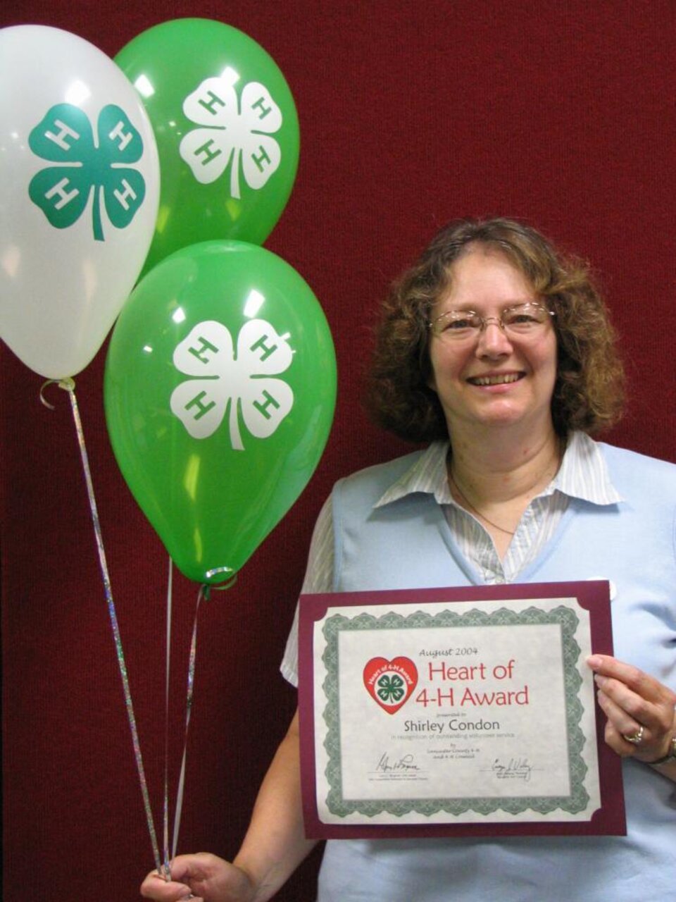 Shirley Condon holding balloons and a certificate 