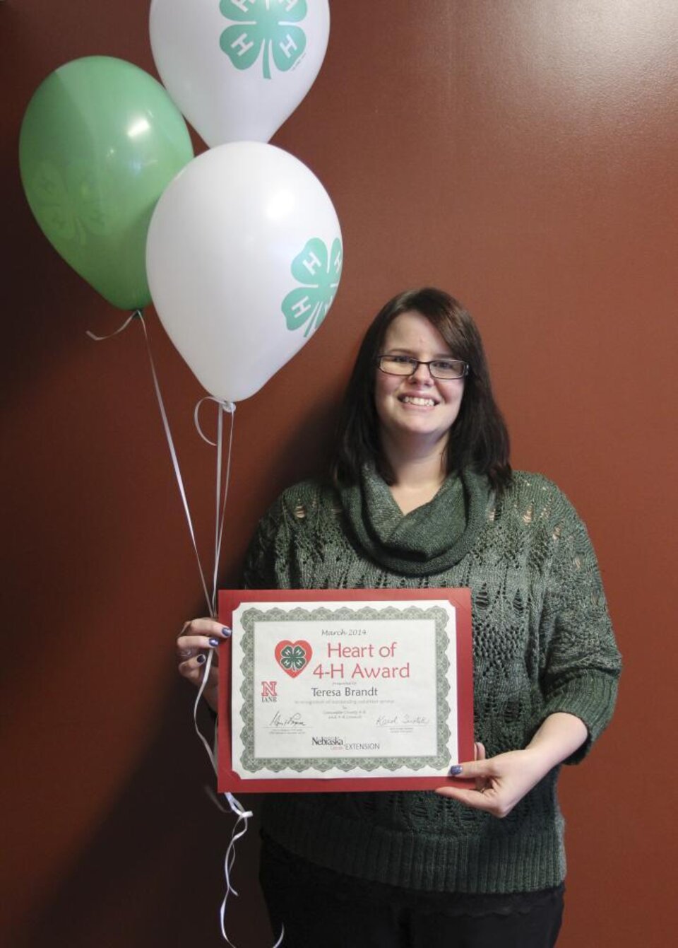 Teresa Brandt holding 4-H balloons and a certificate. 