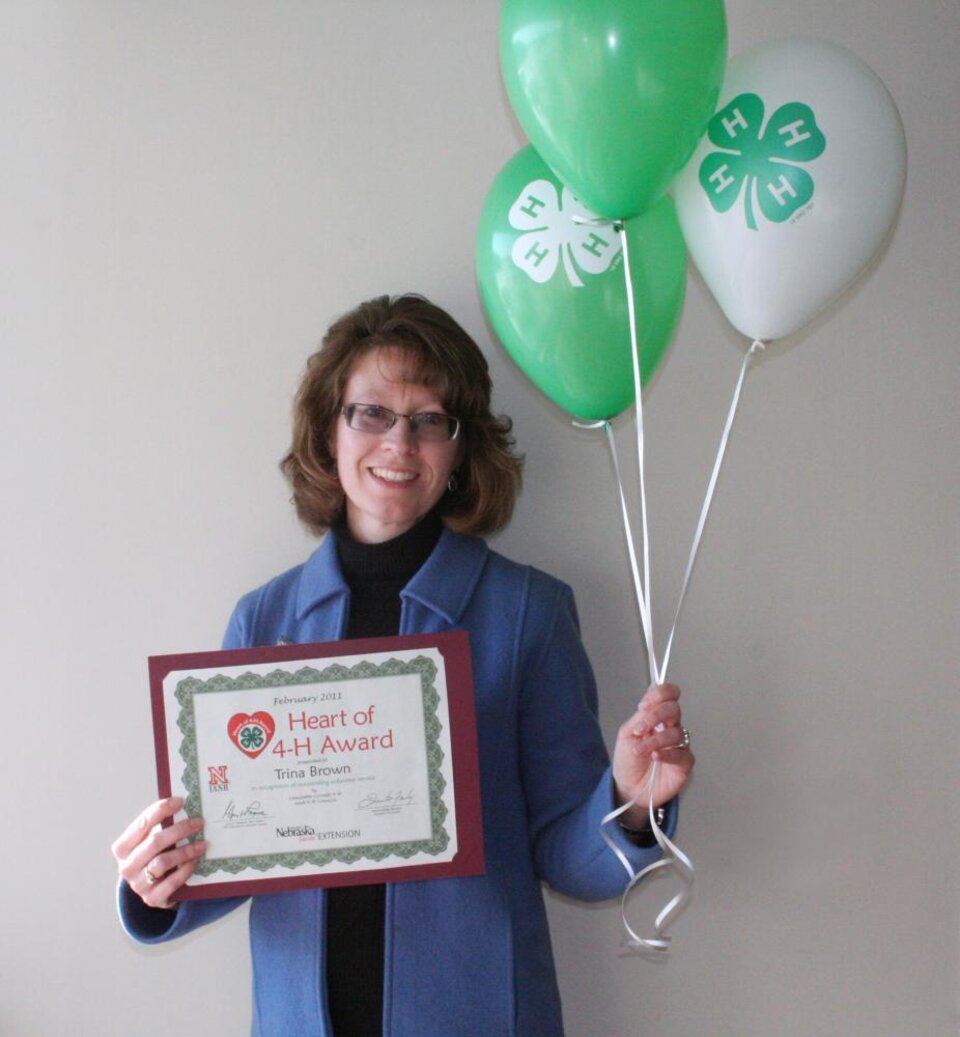 Trina Brown holding 4-H balloons and a certificate 