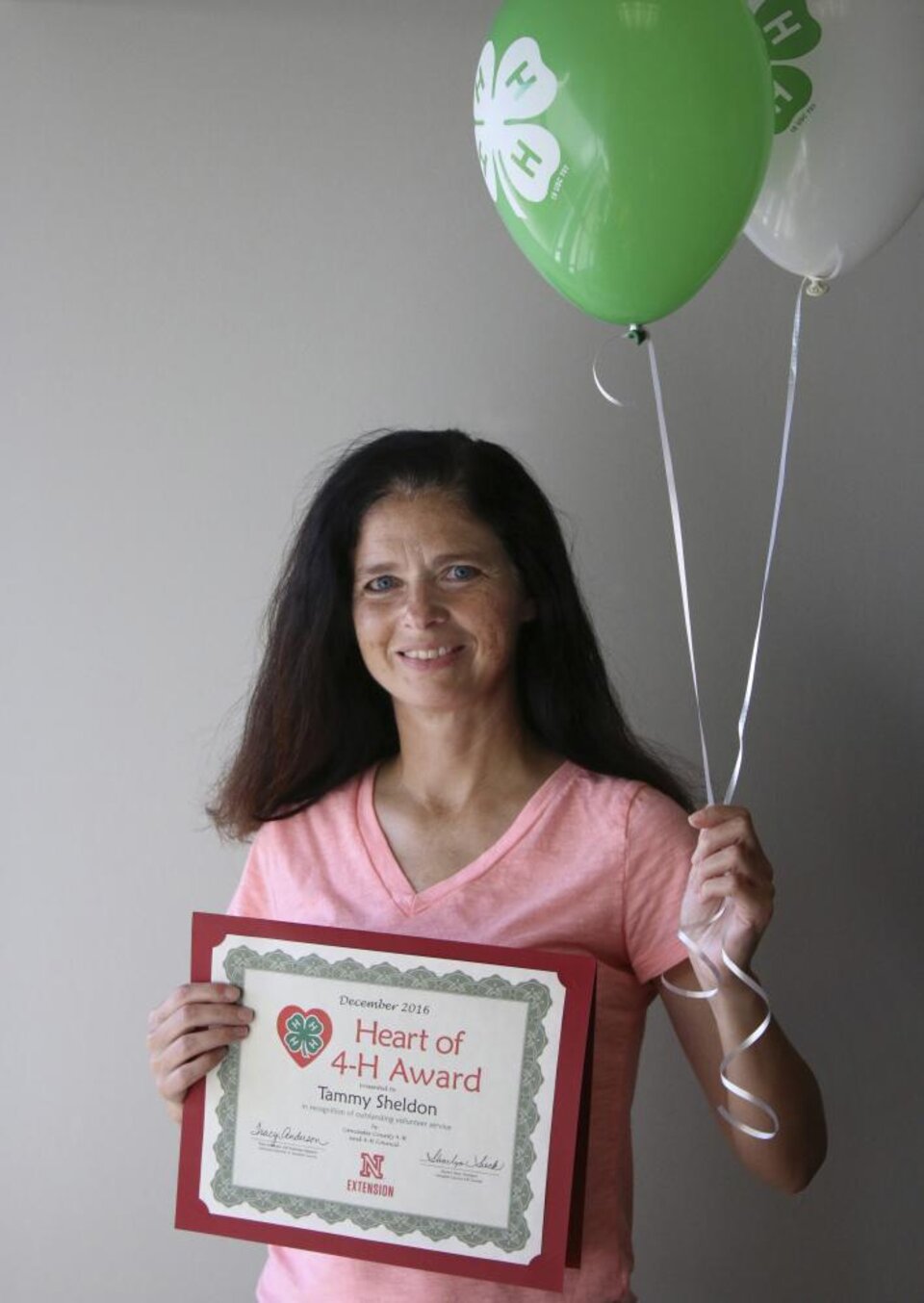 Tammy Sheldon holding 4-H balloons and a certificate. 