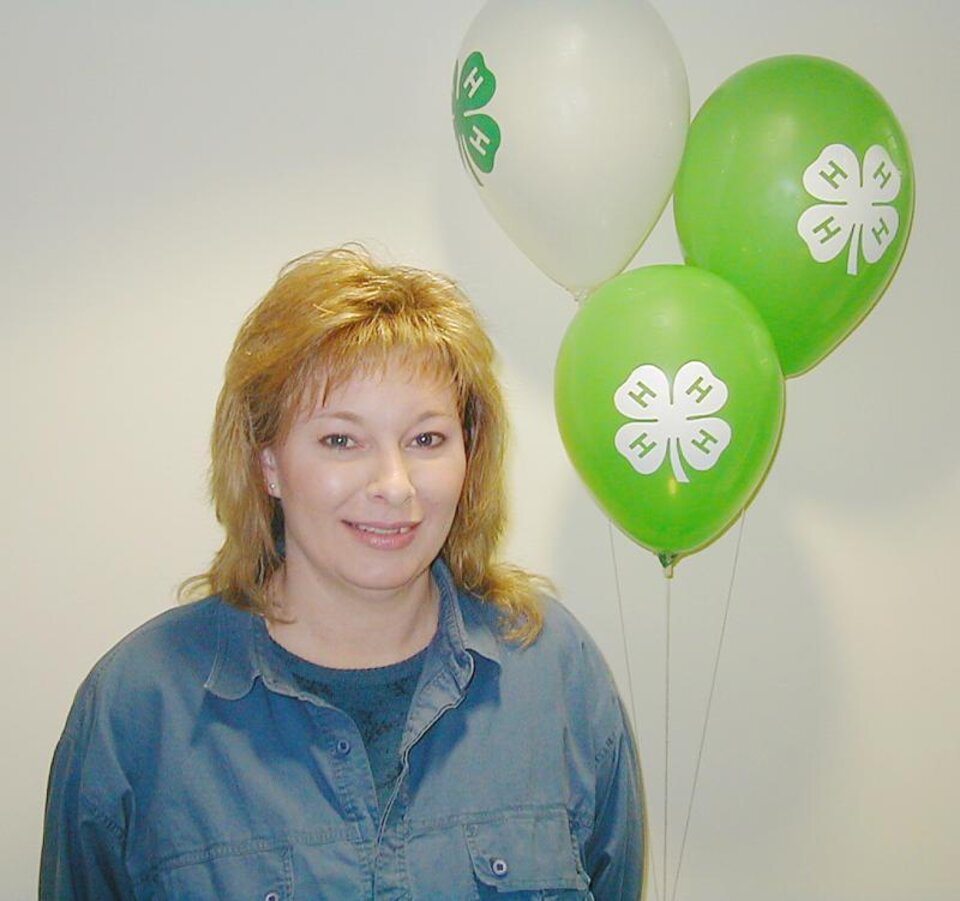 Terri Whisler standing with white and green balloons 