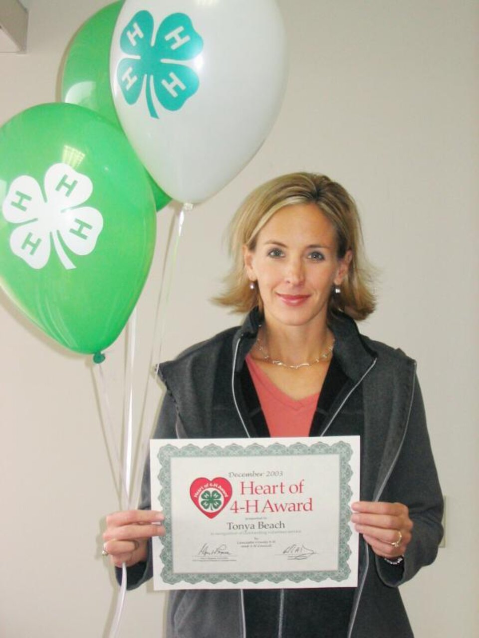 Tonya Beach holding balloons and a certificate. 