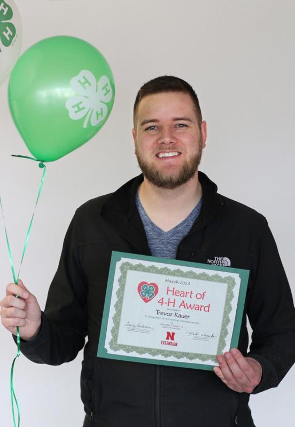 Trevor Kauer holding certificate and balloons. 