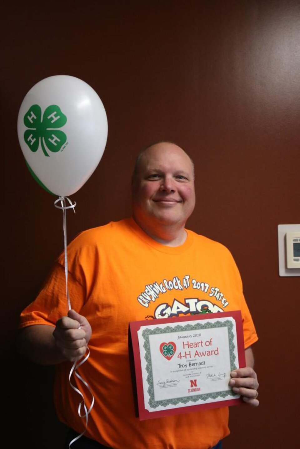 Troy Bernadt holding 4-H balloons and a certificate. 