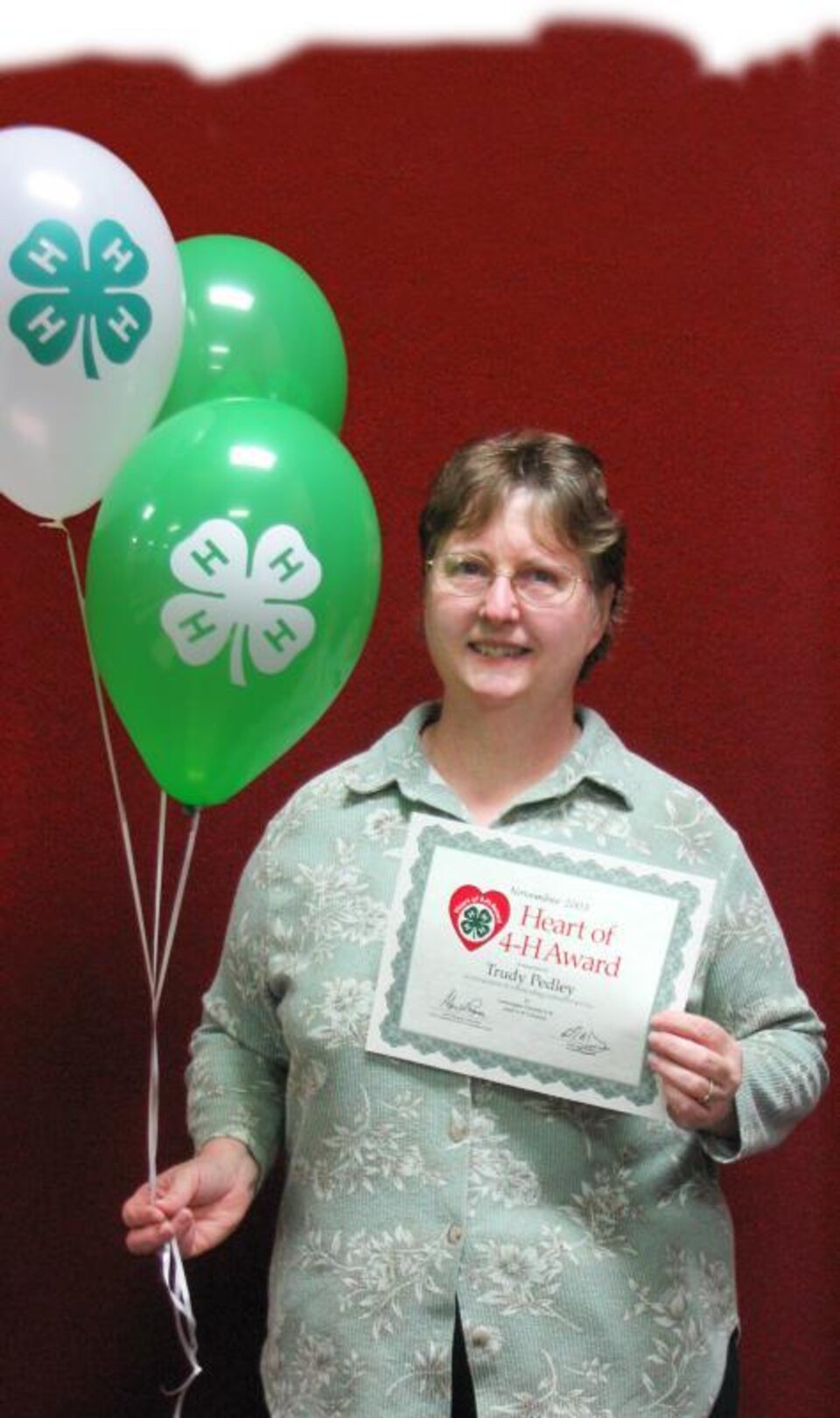 Trudy Pedley holding balloons and a certificate. 