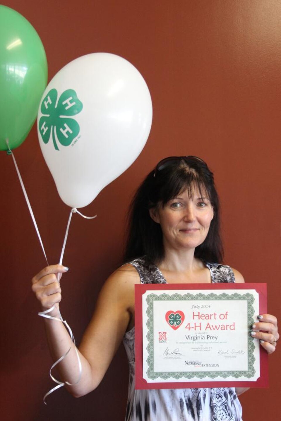 Virginia Prey holding 4-H balloons and a certificate. 