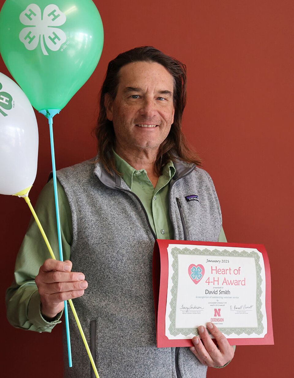 David Smith holding a certificate and balloons