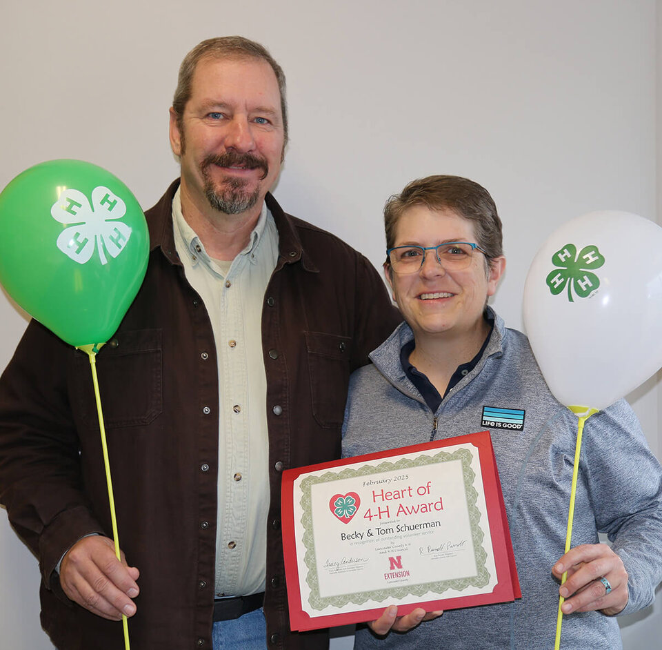 Tom & Becky Schuerman holding balloons and certificate.