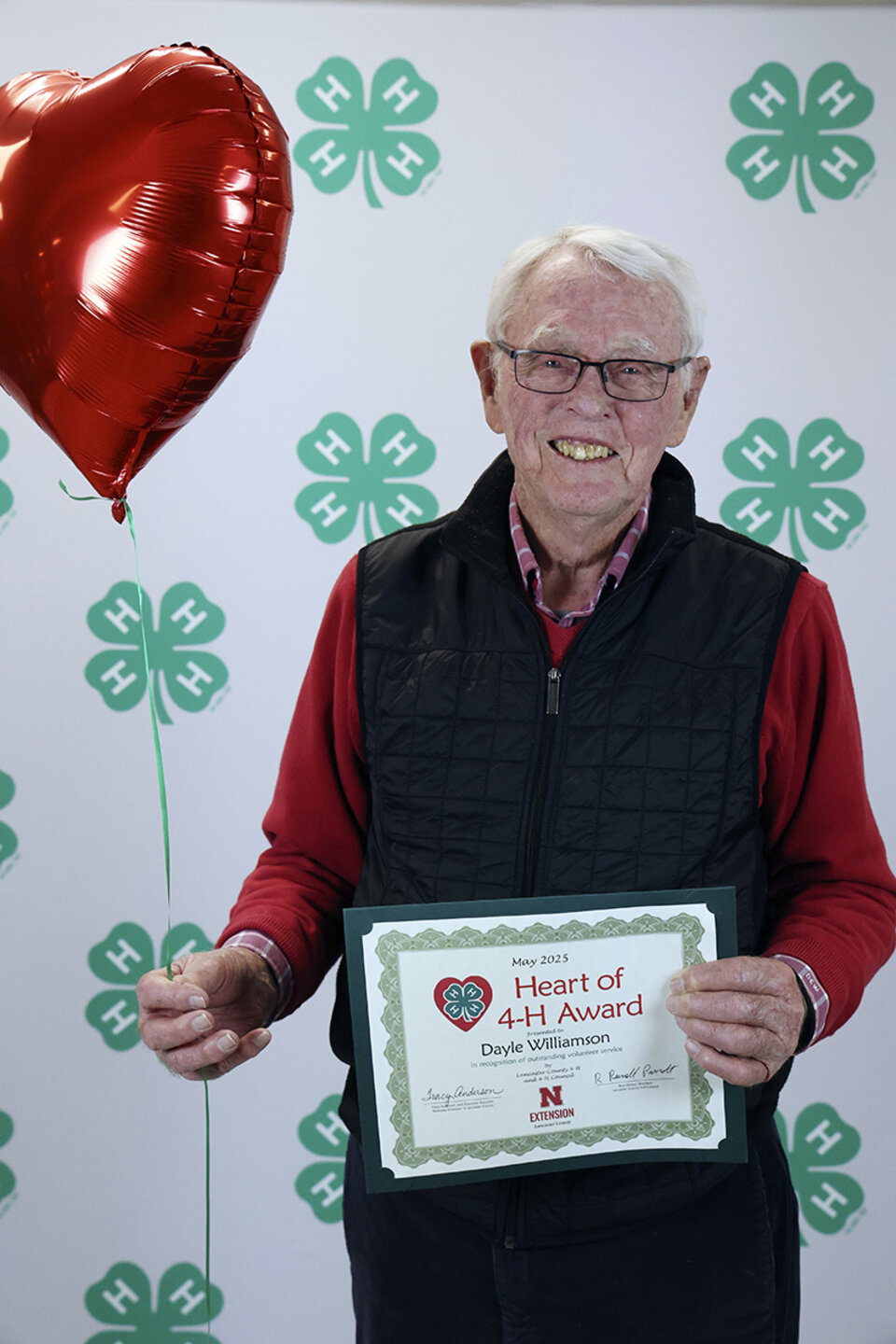Dayle Williamson Man holding heart-shaped balloon and certificate which says Heart of 4-H Award