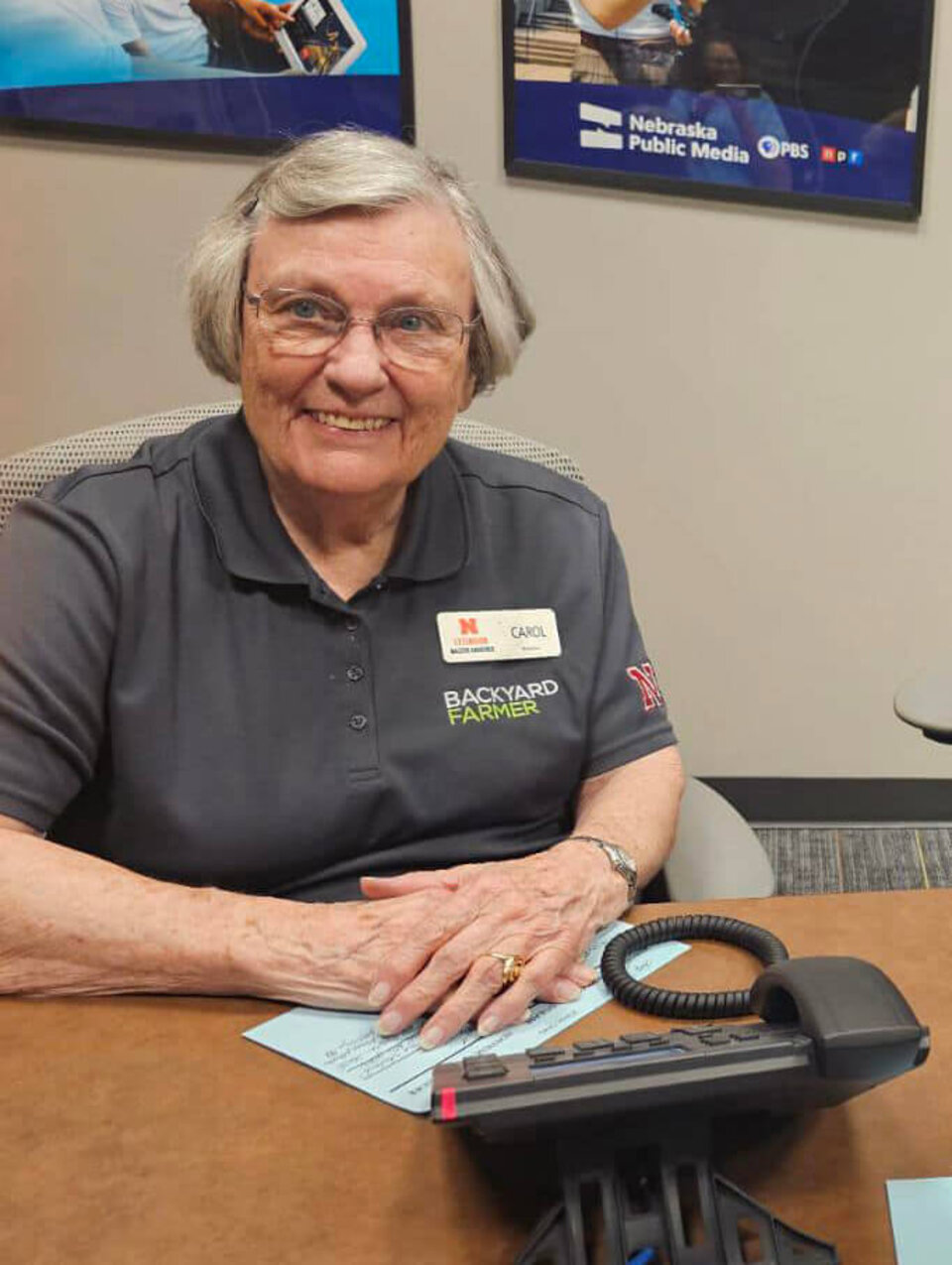 Carol Rustad Smiling woman sitting at a desk with a phone in front of her