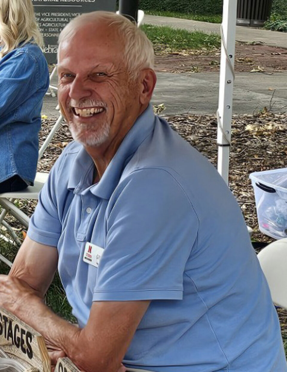 A man smiling outdoors under a booth tent