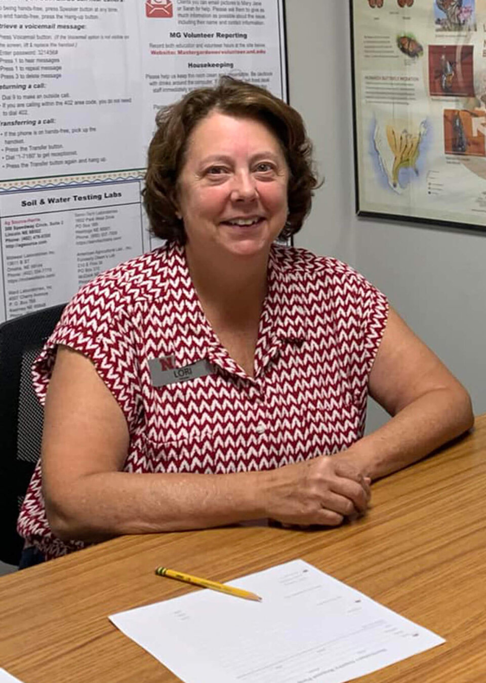 Smiling woman sitting at a desk paperwork in front of her