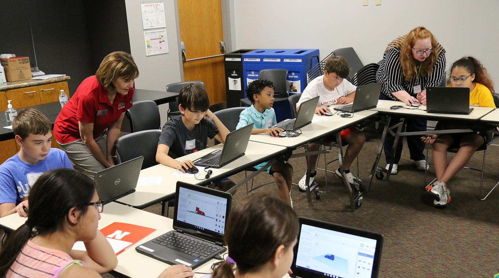 Group of youth at laptops with helpful adults